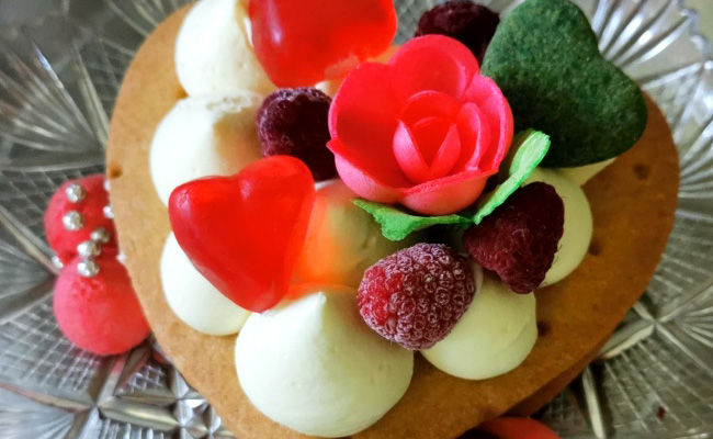 Creme tart a forma di cuore, base biscotto e crema chantilly, con decori a tema