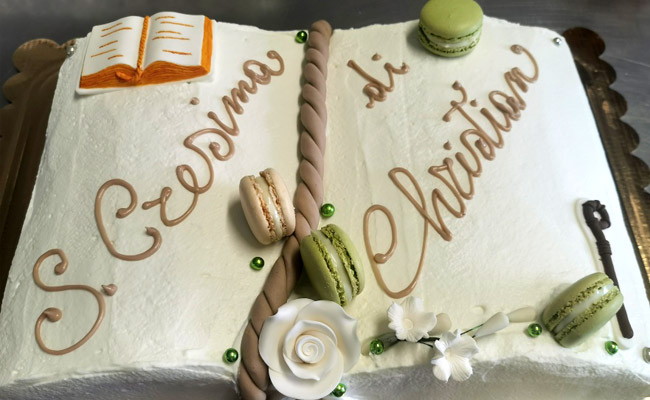 Torta a forma di libro decorata con toni di colore verde e beige.