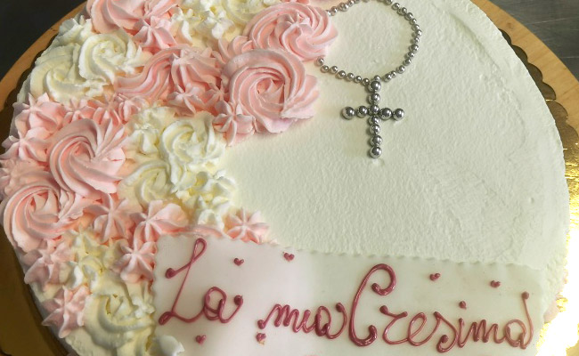 Torta spatolata con panna e decorata con panna bianca e colorata.