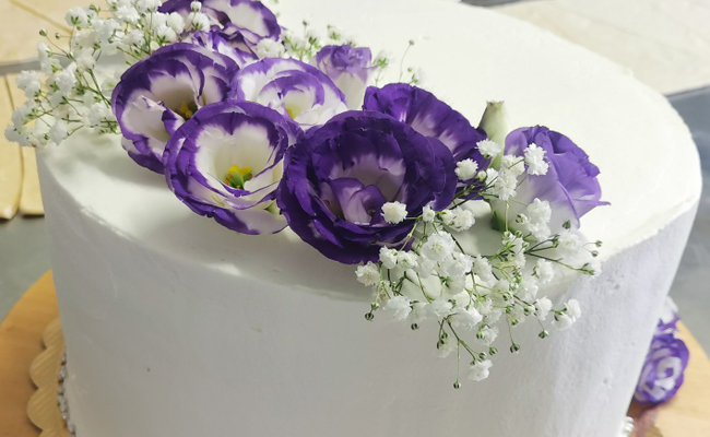 Torta per laurea, spatolata liscia con panna, decorazione di soli fiori freschi.
