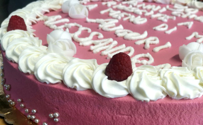 Torta farcita a doppio strato, decorata con panna colorata, scritta Ugly e perline argento