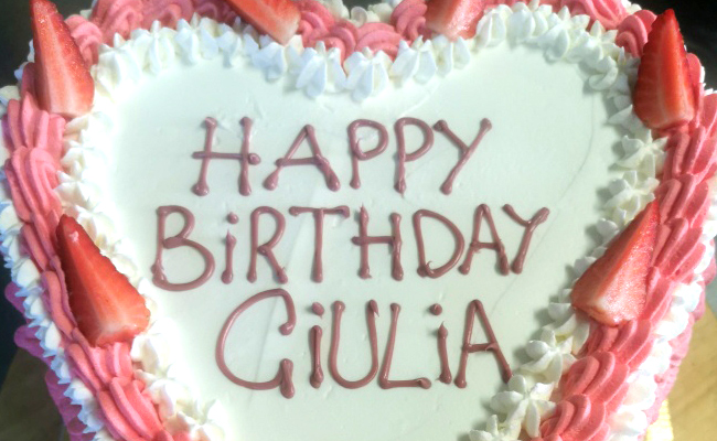 Torta ugly a forma di cuore, decorata con panna colorata e fragole.