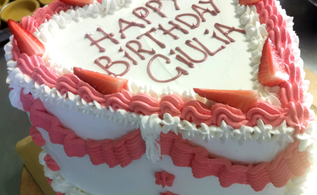 Torta ugly a forma di cuore, decorata con panna colorata e fragole.