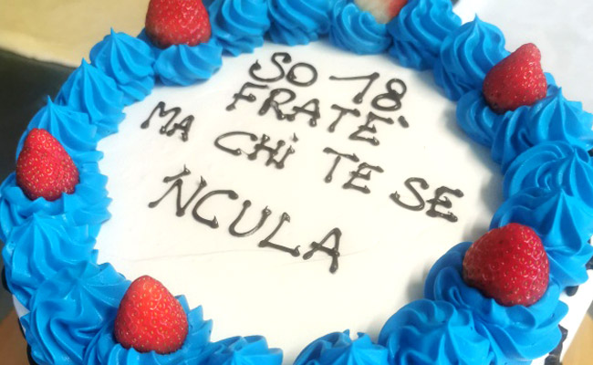 Torta alta, spatolata con panna bianca e decorata con panna colorata e fragole