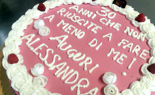 Torta farcita a doppio strato, decorata con panna colorata, scritta Ugly e perline argento