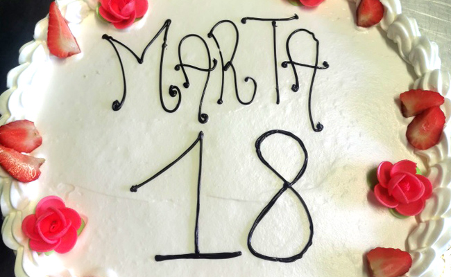 Torta vegana con crema e frutta, rifinita con panna e decorata con fragole e panna.