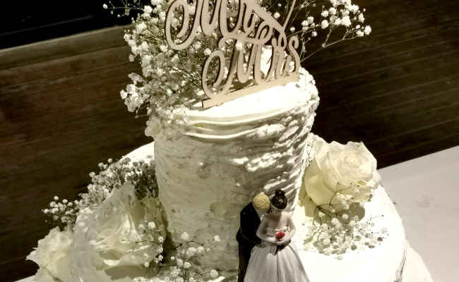 Torta a 3 piani decorata con panna e fiori freschi, farcita con fragole e frutti di bosco, spatolata a righe