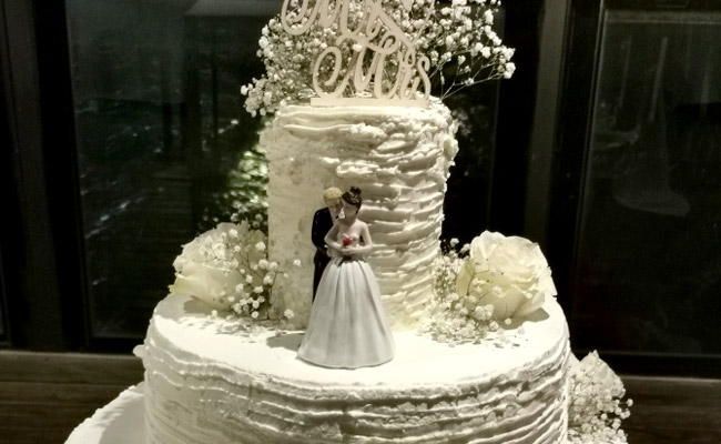 Torta a 3 piani decorata con panna e fiori freschi, farcita con fragole e frutti di bosco, spatolata a righe
