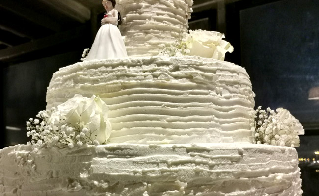 Torta a 3 piani decorata con panna e fiori freschi, farcita con fragole e frutti di bosco, spatolata a righe